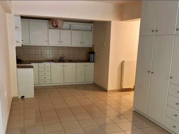 Ενιαίος χώρος studio με ανοιχτή κουζίνα, λευκά ντουλάπια και μεγάλη ντουλάπα, στα Κάτω Πατήσια Αθήνας.
