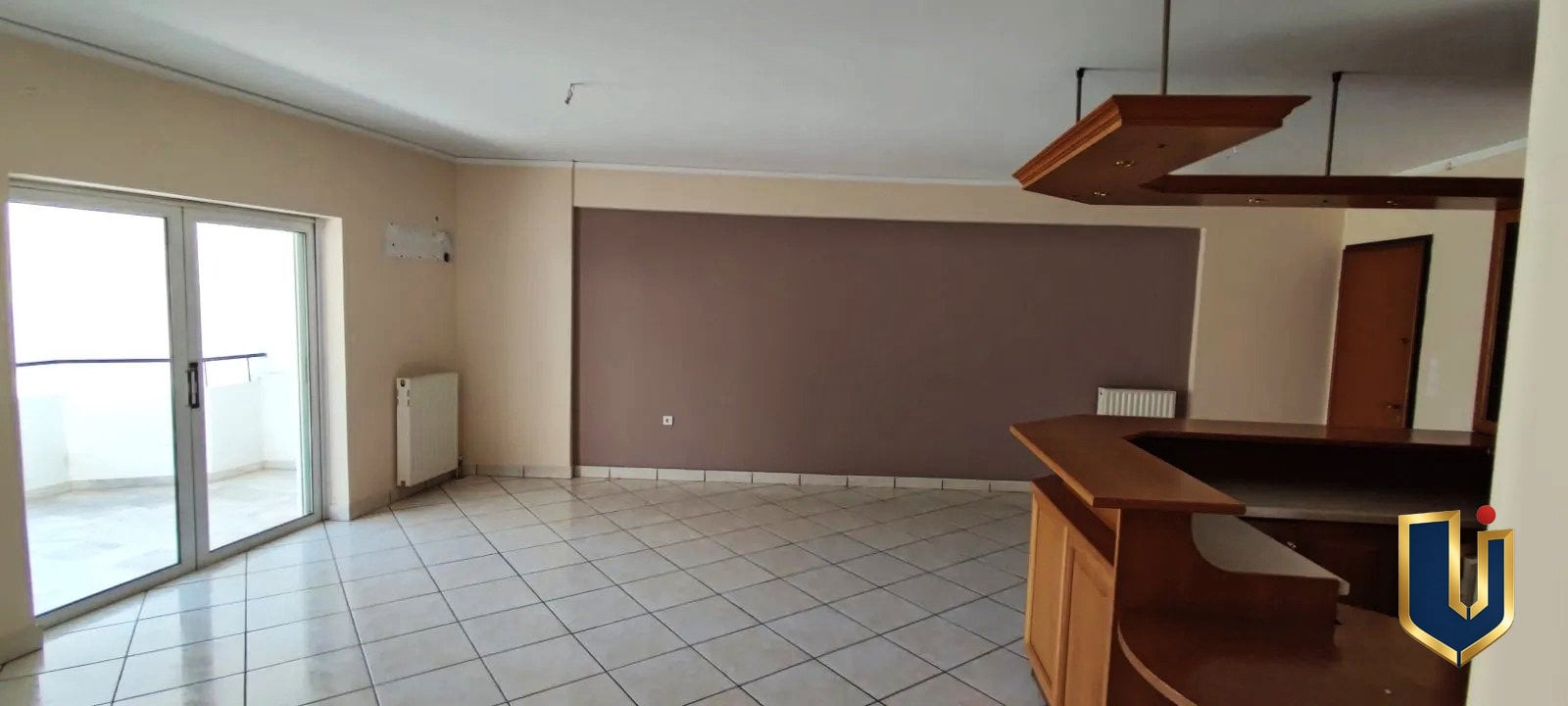 Σαλόνι με πρόσβαση στο μπαλκόνι | Άγιος Ελευθέριος | 150-1048 Σαλόνι με μπαλκονόπορτες αριστερά και ξύλινο πάσο κουζίνας δεξιά, σε διαμέρισμα στον Άγιο Ελευθέριο Αθήνας.