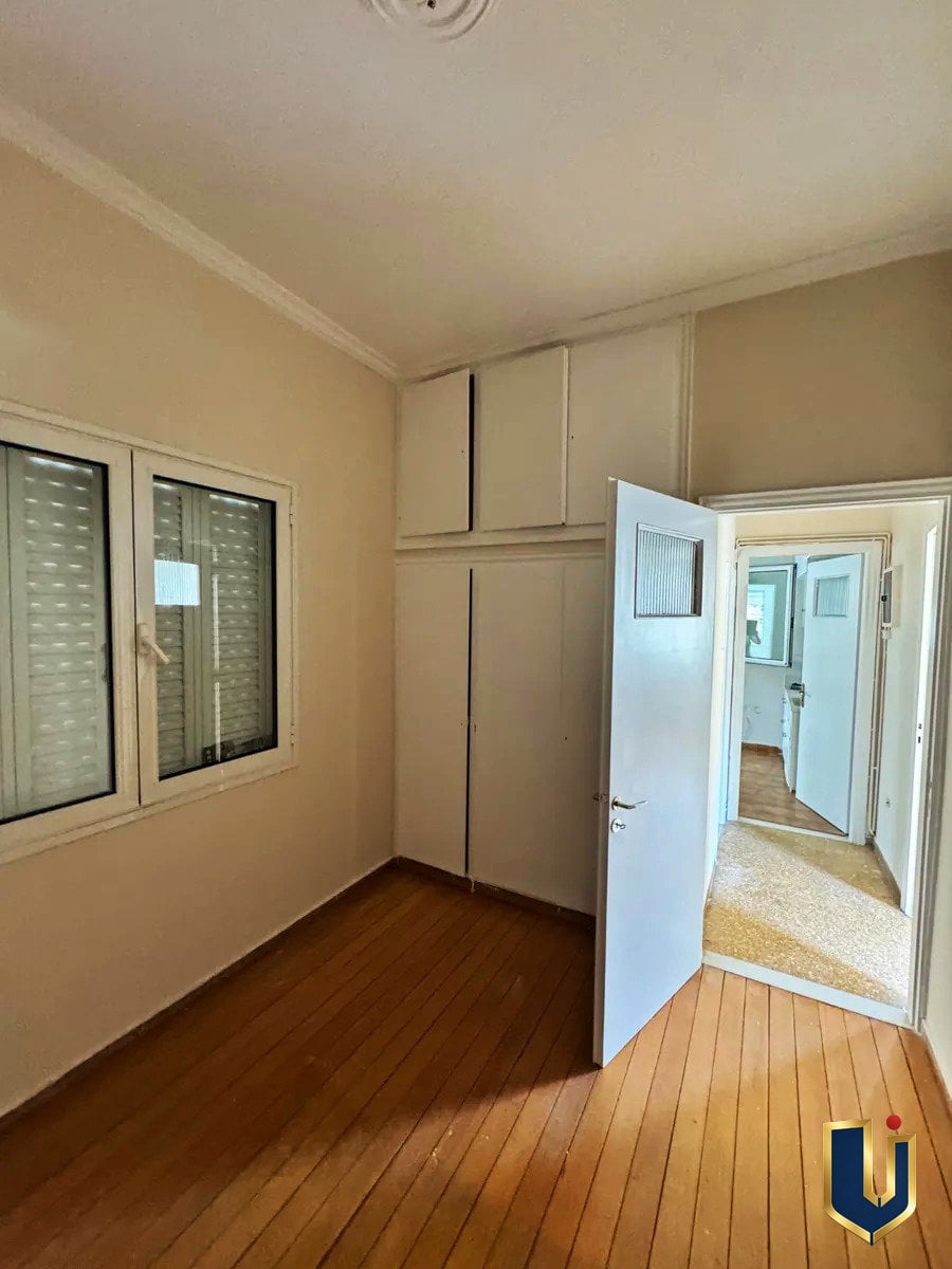 Παιδικό δωμάτιο στην Κυπριάδου | Urban Keys Athens Υπνοδωμάτιο με ξύλινο δάπεδο, παράθυρο και ανοιχτή πόρτα προς τον διάδρομο στην Κυπριάδου – Άνω Πατήσια.